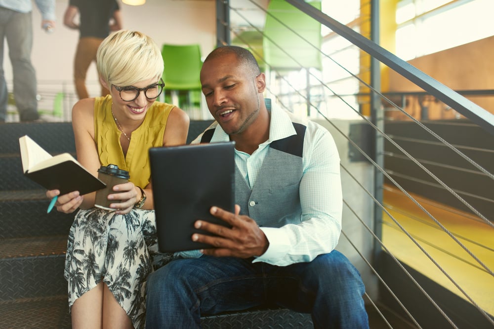 Two business people smiling looking at tablet