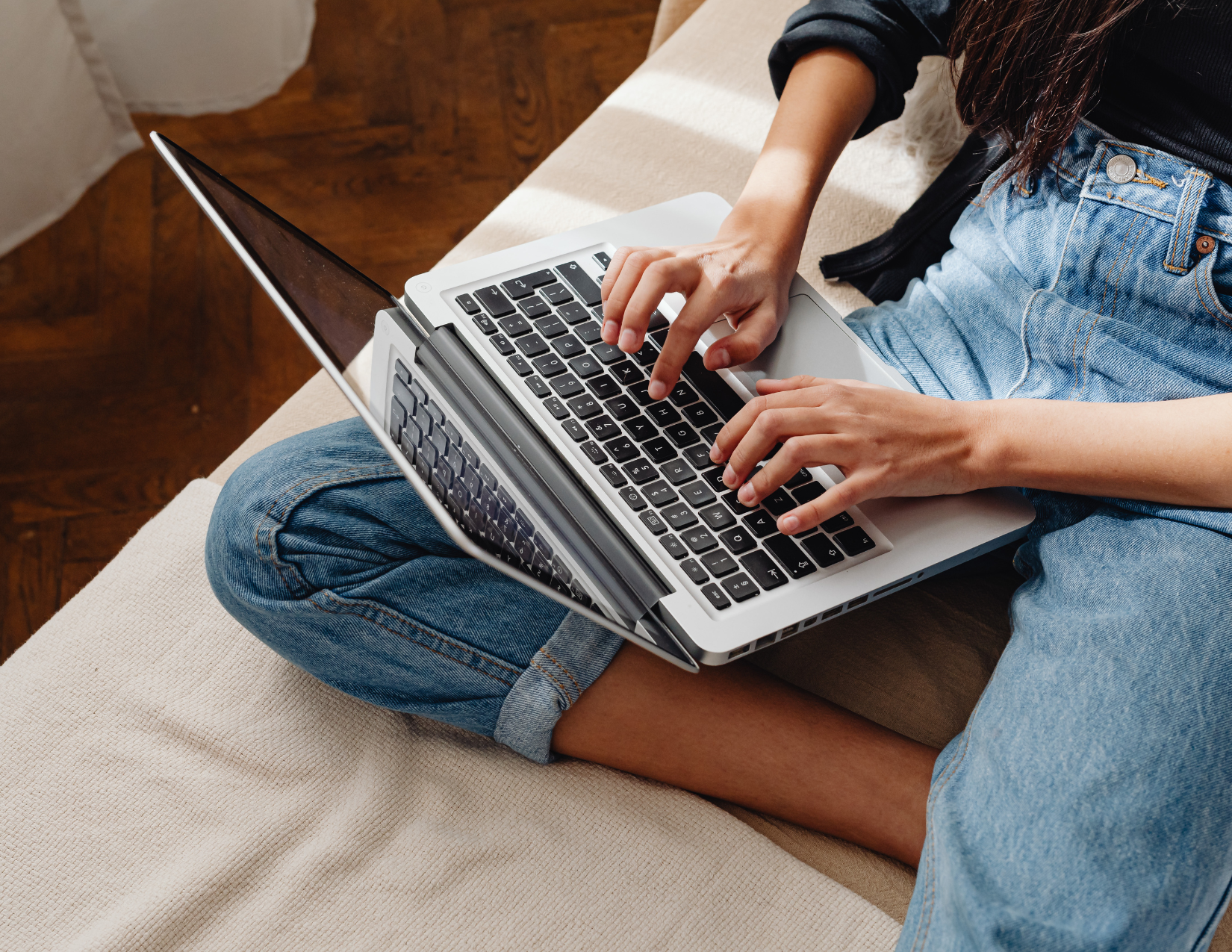 Woman sitting in bed typing on laptop keyboard