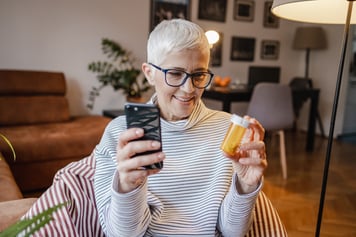 Woman with glasses using cell phone for telemedicine video call to ask about her prescription