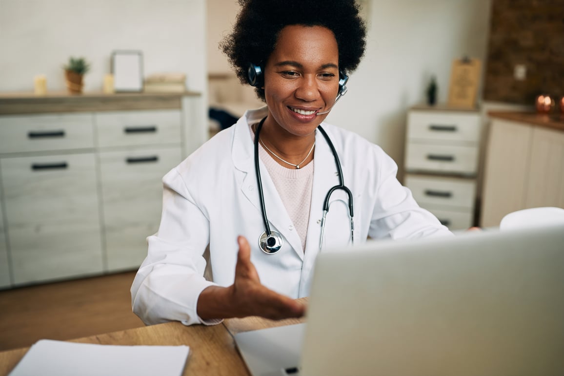 Female doctor in white labcoat using laptop on video telemedicine call with patient