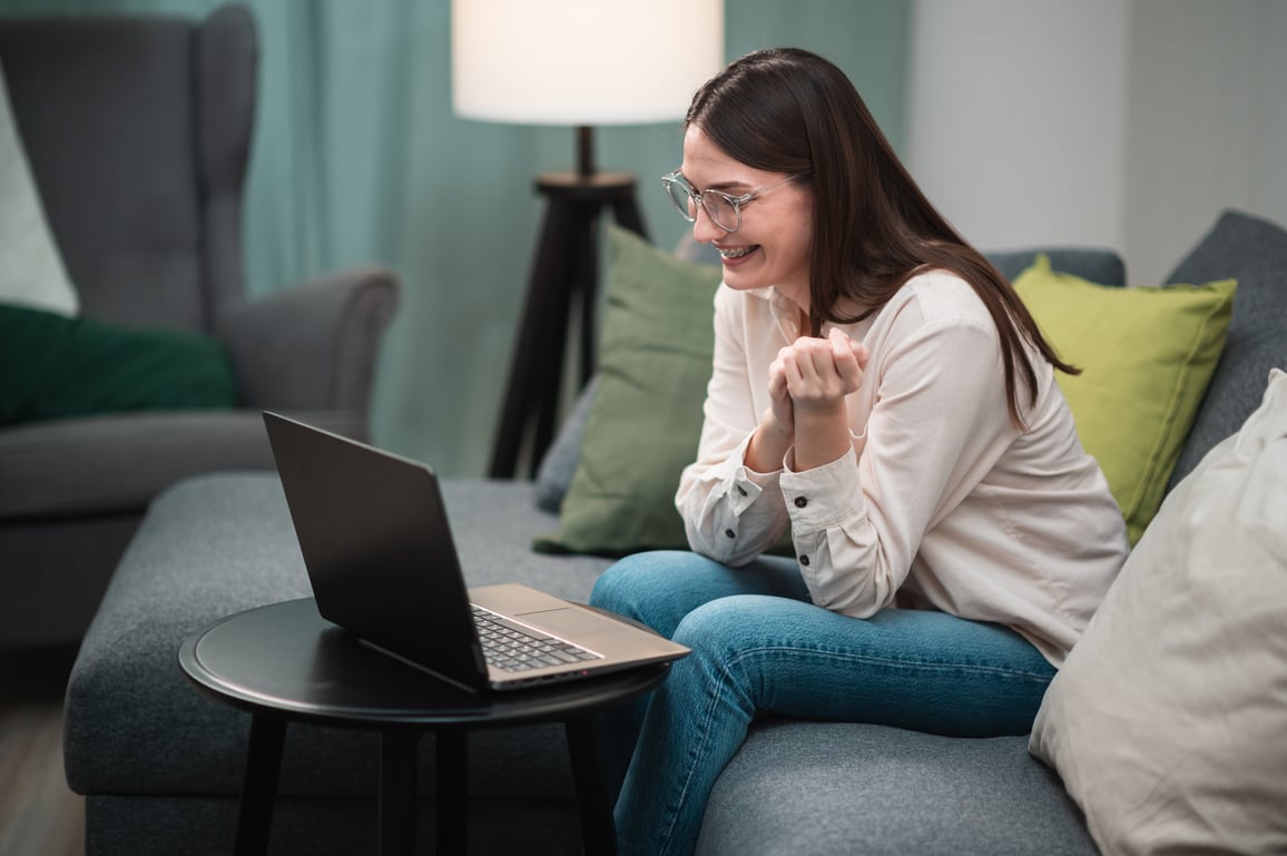 Young female patient sitting on sofa using laptop to speak on video call