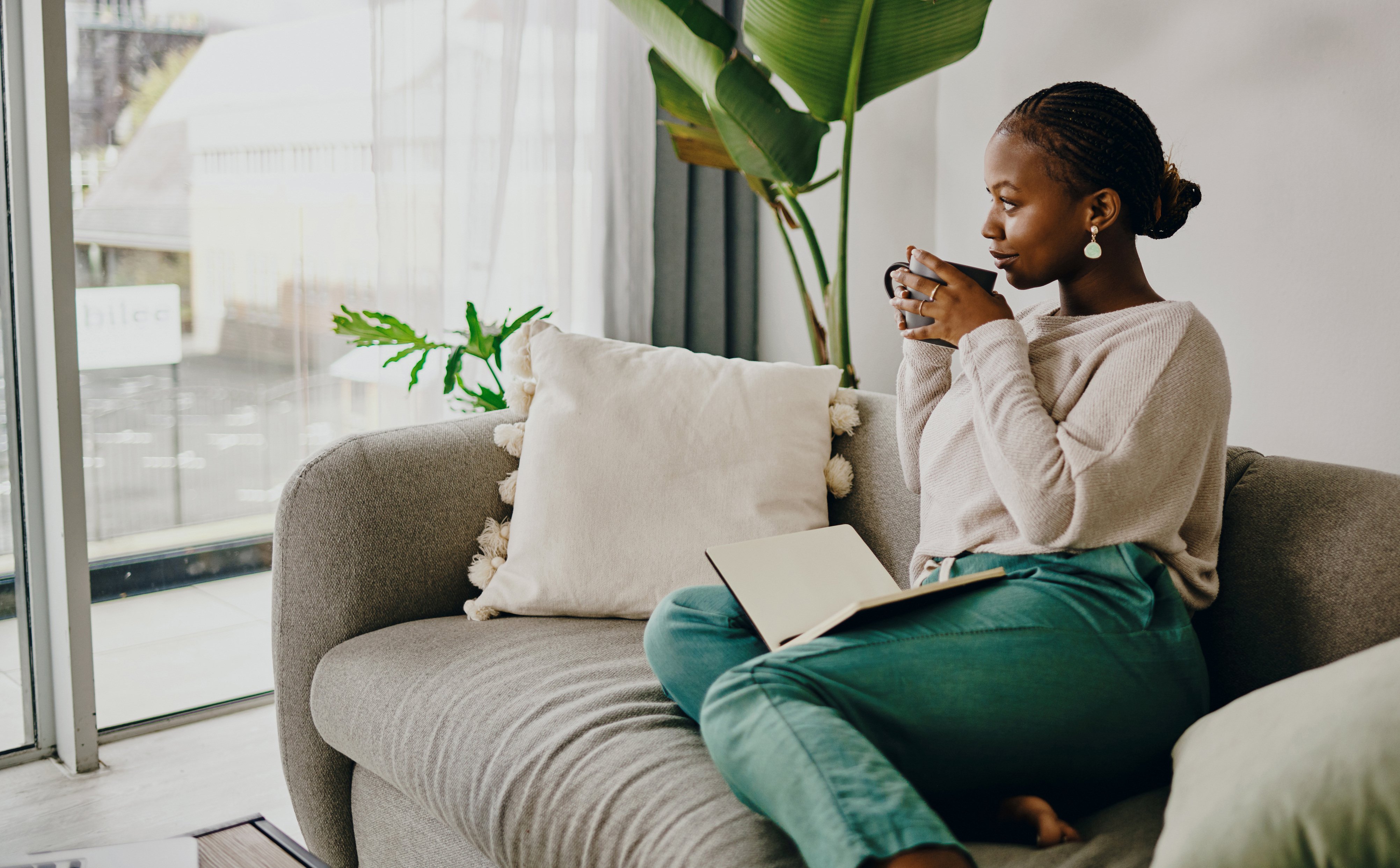 Woman drinking out of a mug on a sofa