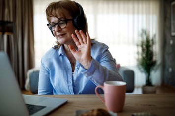 Female patient waving with hand and speaking into tablet for video call with healthcare provider