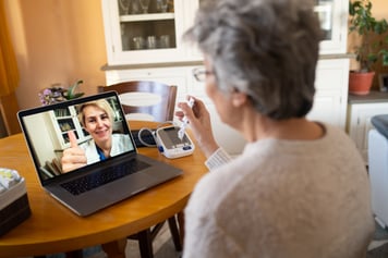 Elderly female patient using laptop for a virtual care appointment with her female healthcare provider