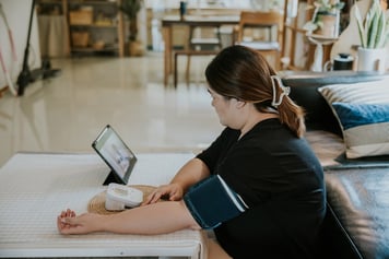 Yougn female patient using blood pressure cuff on her arm during a telemedicine call with her healthcare provider