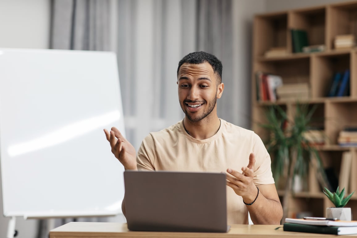 Happy man using laptop on telemedicine video call while sitting at desk