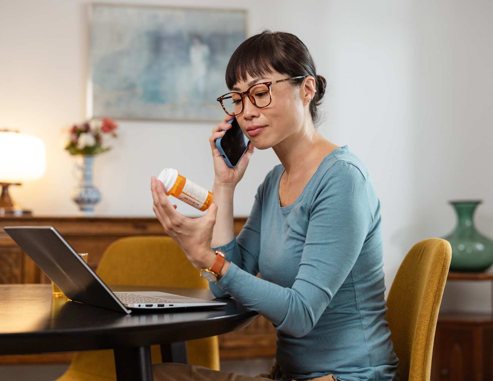 Woman on the phone looking at a prescription bottle