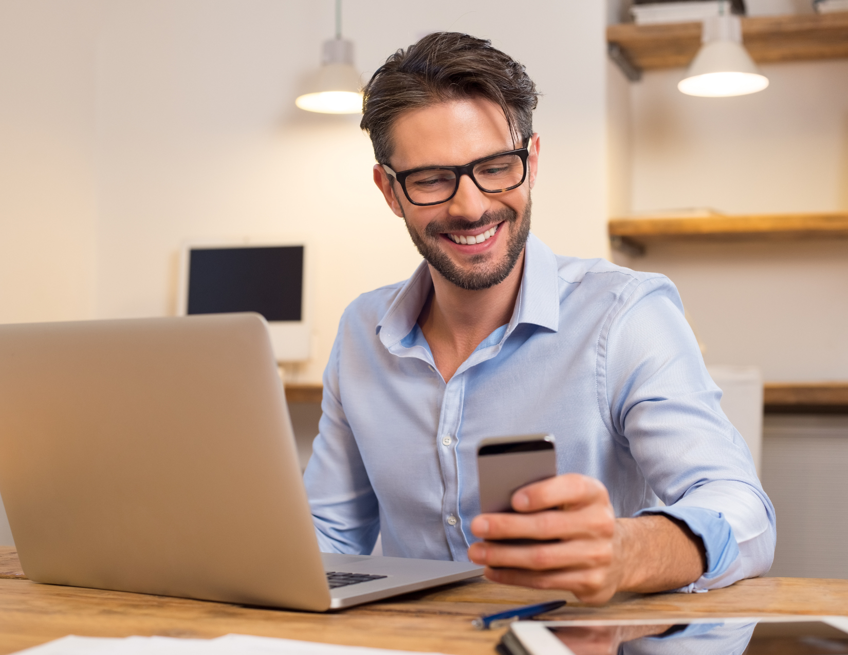 Young man at desk looking at his phone